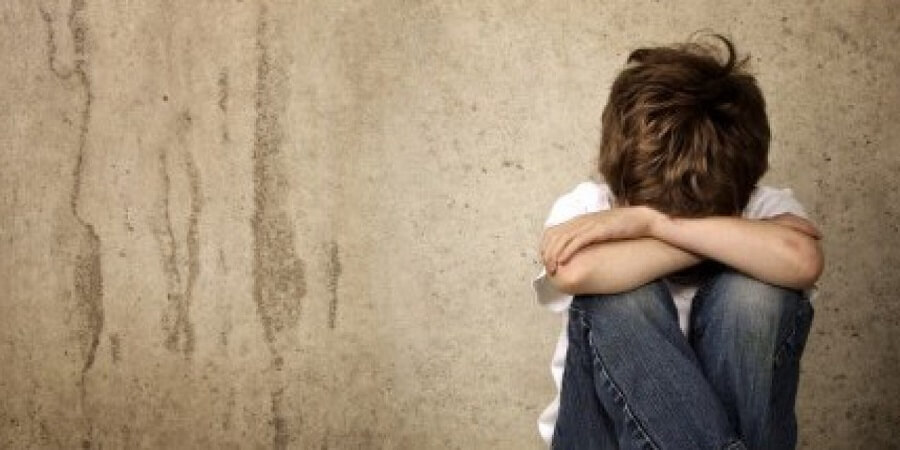 young boy sitting with head in his arms