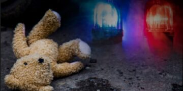 A teddy on the ground with emergency lights in the background